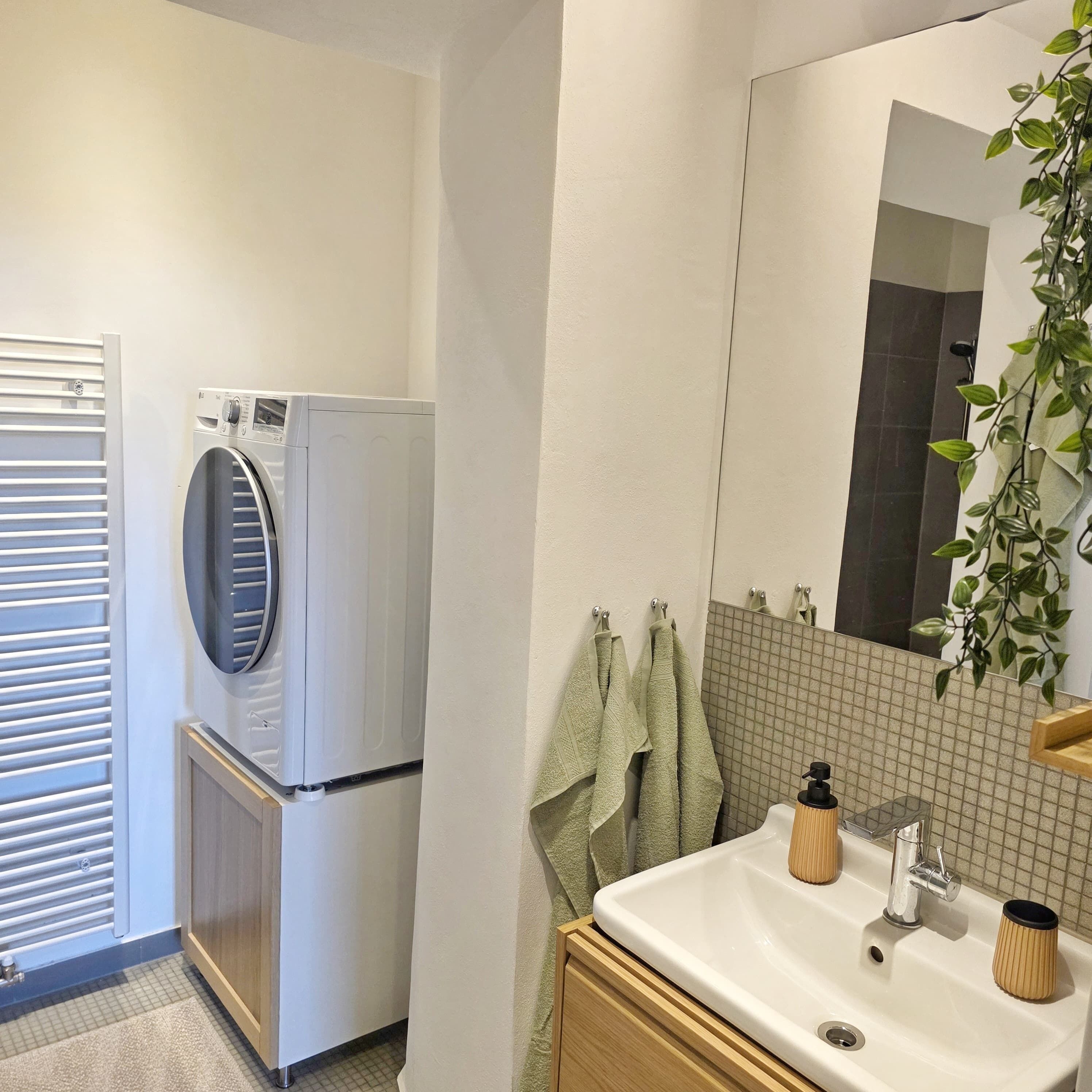 A compact bathroom with a built-in washer and dryer, a sink with a mirror, and a towel rack.