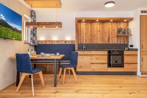 Eine moderne Küche mit Holzschränken, einem eingebauten Ofen und einem Essbereich mit Tisch und Stühlen.