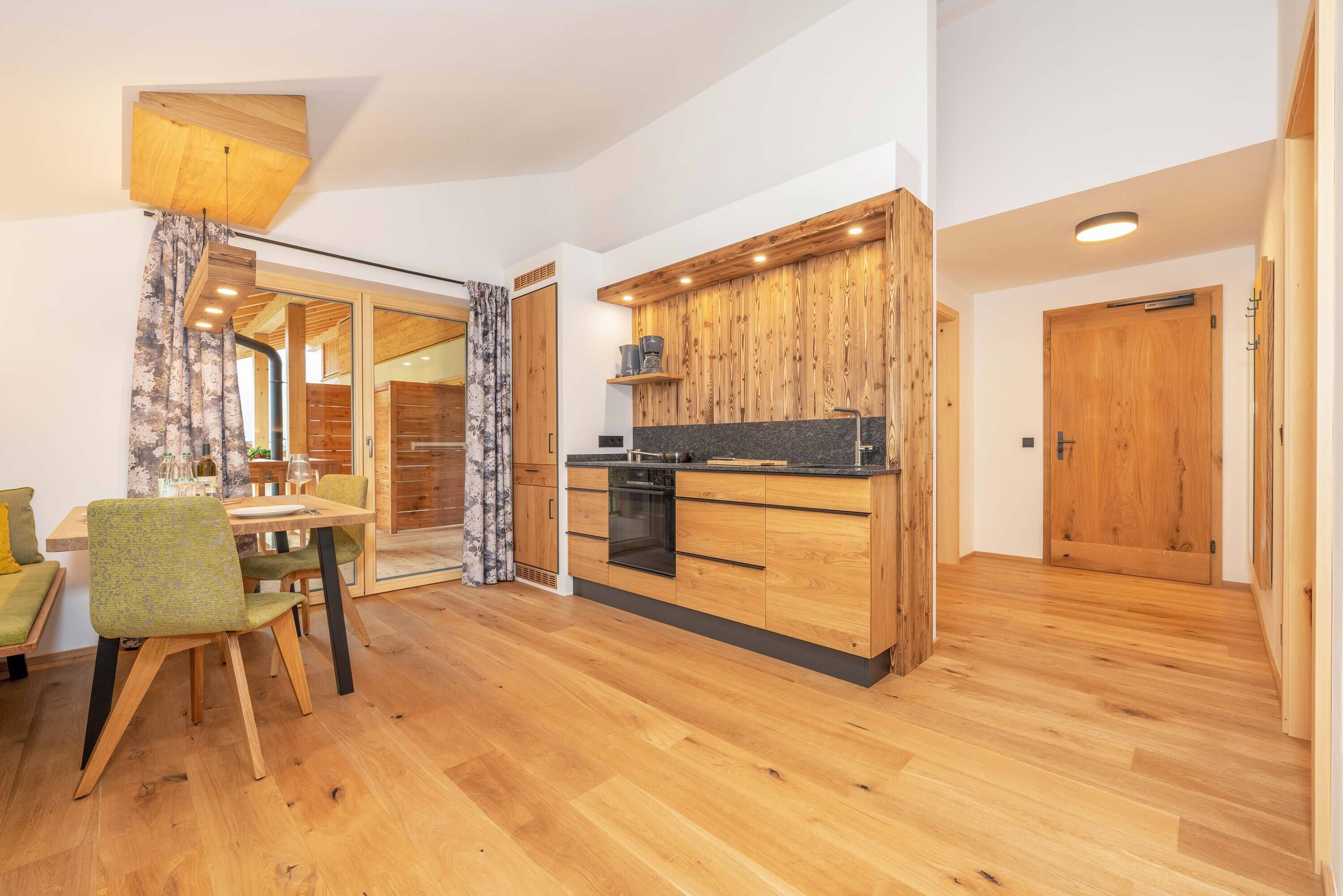 A modern kitchen with wooden cabinets, a built-in oven, and a dining area with a table and chairs.