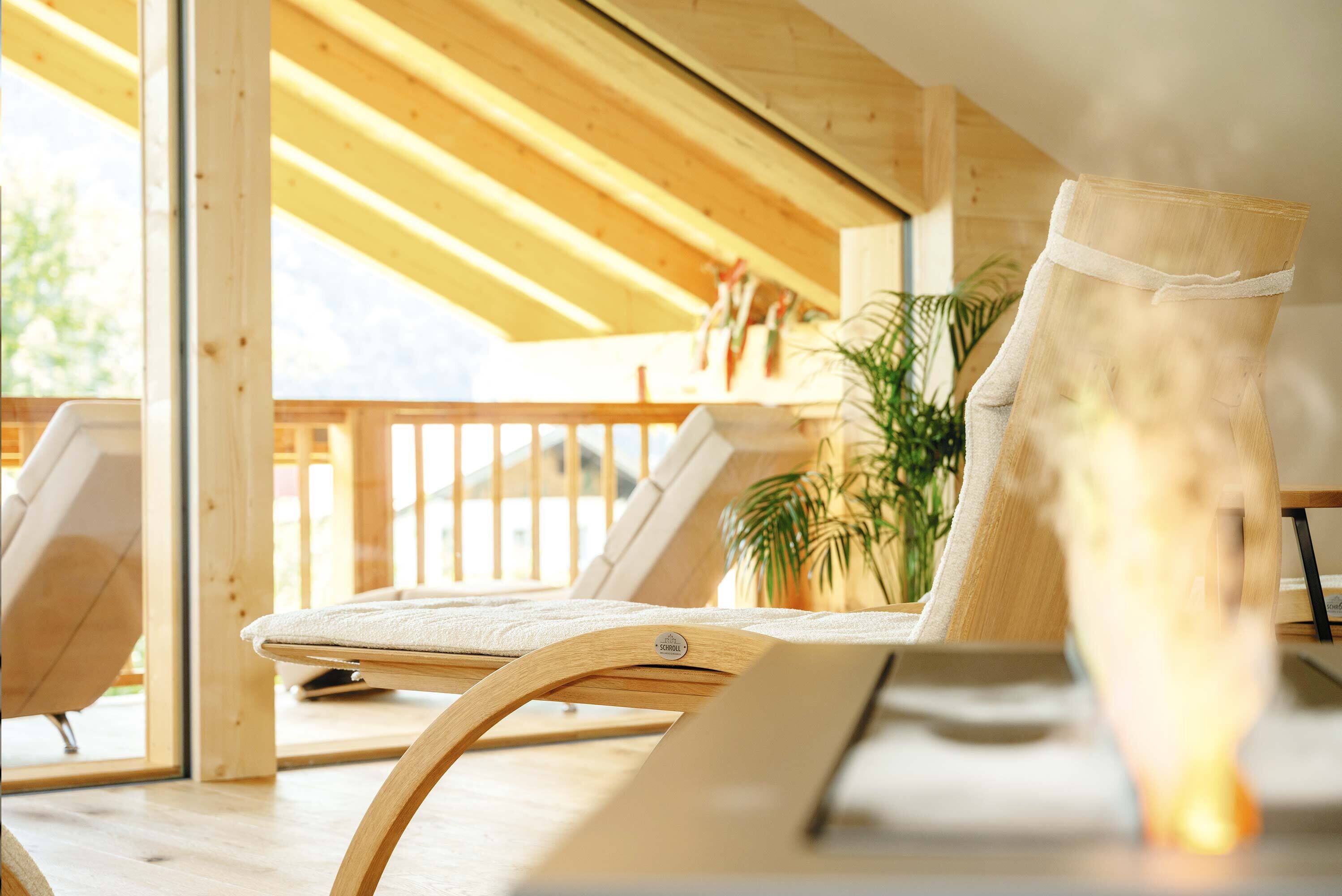 A wooden-framed lounge chair with a cushion, positioned near a window with a view of the outdoors.
