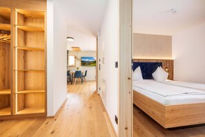 Ett modernt hotellrum med trägolv, en säng med sänggavel, ett skrivbord med stolar och utsikt över ett landskap genom ett fönster.