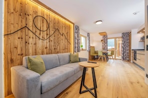 Ein modernes Wohnzimmer mit einer Wandpaneinung aus Holz, einem grauen Sofa und einem kleinen runden Tisch.