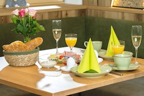 Ein Frühstückstisch mit Brot, einem Blumenstrauß und verschiedenen Frühstücksleckereien.