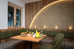 Ein Essbereich mit einer Holzwand, einem Tisch gedeckt mit Frühstücksleckereien und einer Bank.