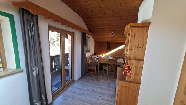 Un intérieur en bois comprenant un coin repas, un meuble en bois et une porte-fenêtre coulissante donnant sur l’extérieur.