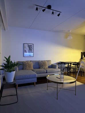 Una sala de estar moderna con sofá, mesa de centro y comedor con sillas.