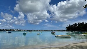 A beach with boats, clear water, and a distant shoreline. - Cdas&Fav Apartment Grand baie Mauritius  (Grand Baie)