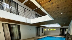 A modern indoor swimming pool with a wooden ceiling and a view of the upper floor. - Cdas&Fav Apartment Grand baie Mauritius  (Grand Baie)