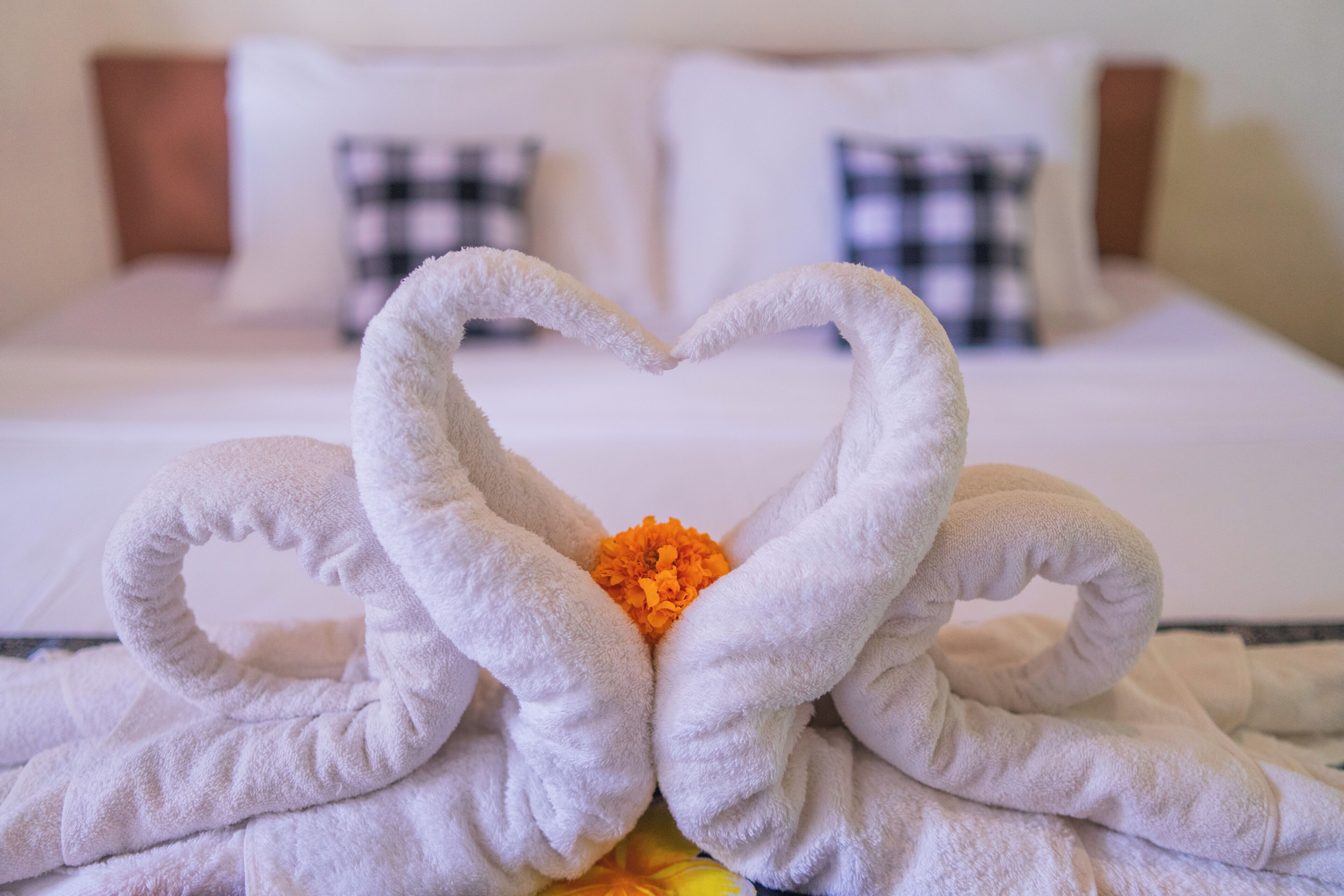 A bed with white linens and a heart-shaped towel arrangement in the center.