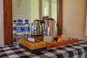 Una mesa con estampado de cuadros que tiene una bandeja con botellas de agua, una cafetera y una taza.