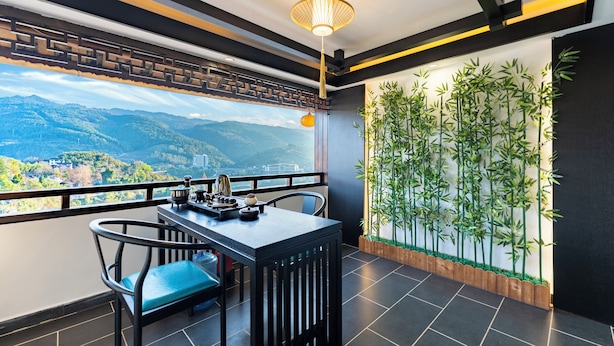 A balcony with a table and chairs, a hanging light fixture, and a bamboo plant wall. - 12C View Homestay (Xiangxi)