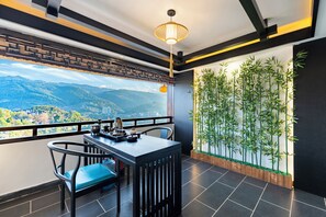 A balcony with a table and chairs, a hanging light fixture, and a bamboo plant wall.