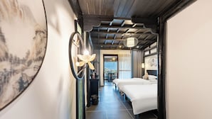 A hotel room with a bed, a desk, a chair, a small table, a trash bin, and a view of the outside. - 12C View Homestay (Xiangxi)