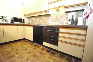 Eine Küche mit Geschirrspüler, Backofen, Mikrowelle und gefliestem Fliesenspiegel.