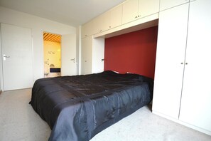 Ein Schlafzimmer mit Bett, Kleiderschrank und einer roten Wand.