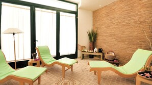 A spa room with wooden chairs, a massage table, a large window, and a brick wall. - Villa in Cecina Mare Near Sandy Beach (Cecina)