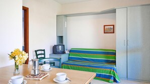 A compact room with a bed, a small table with a coffee maker, cups, and a vase of flowers. - Villa in Cecina Mare Near Sandy Beach (Cecina)