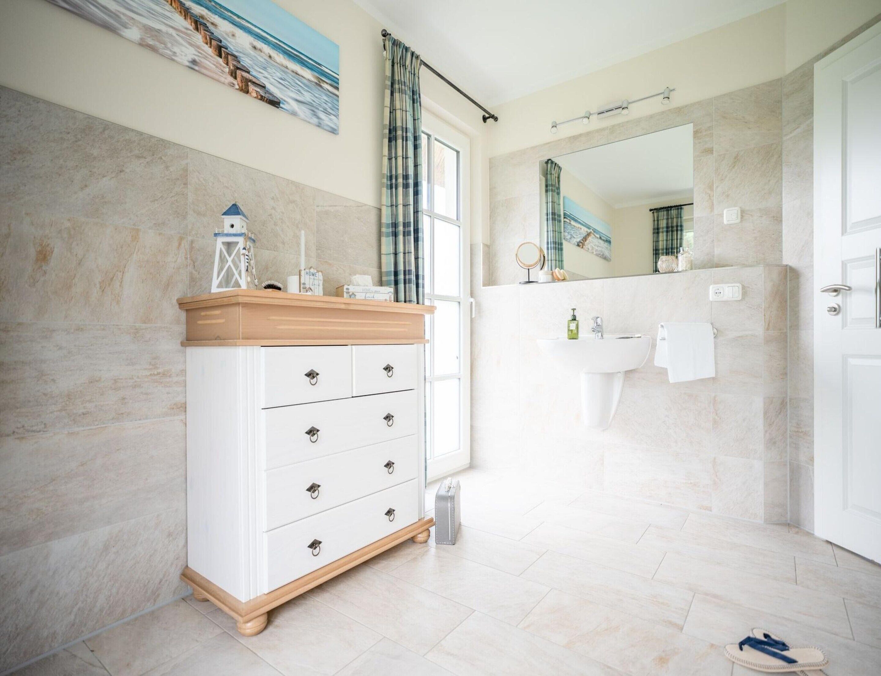 A modern bathroom with a white vanity, a large mirror, and a sink.