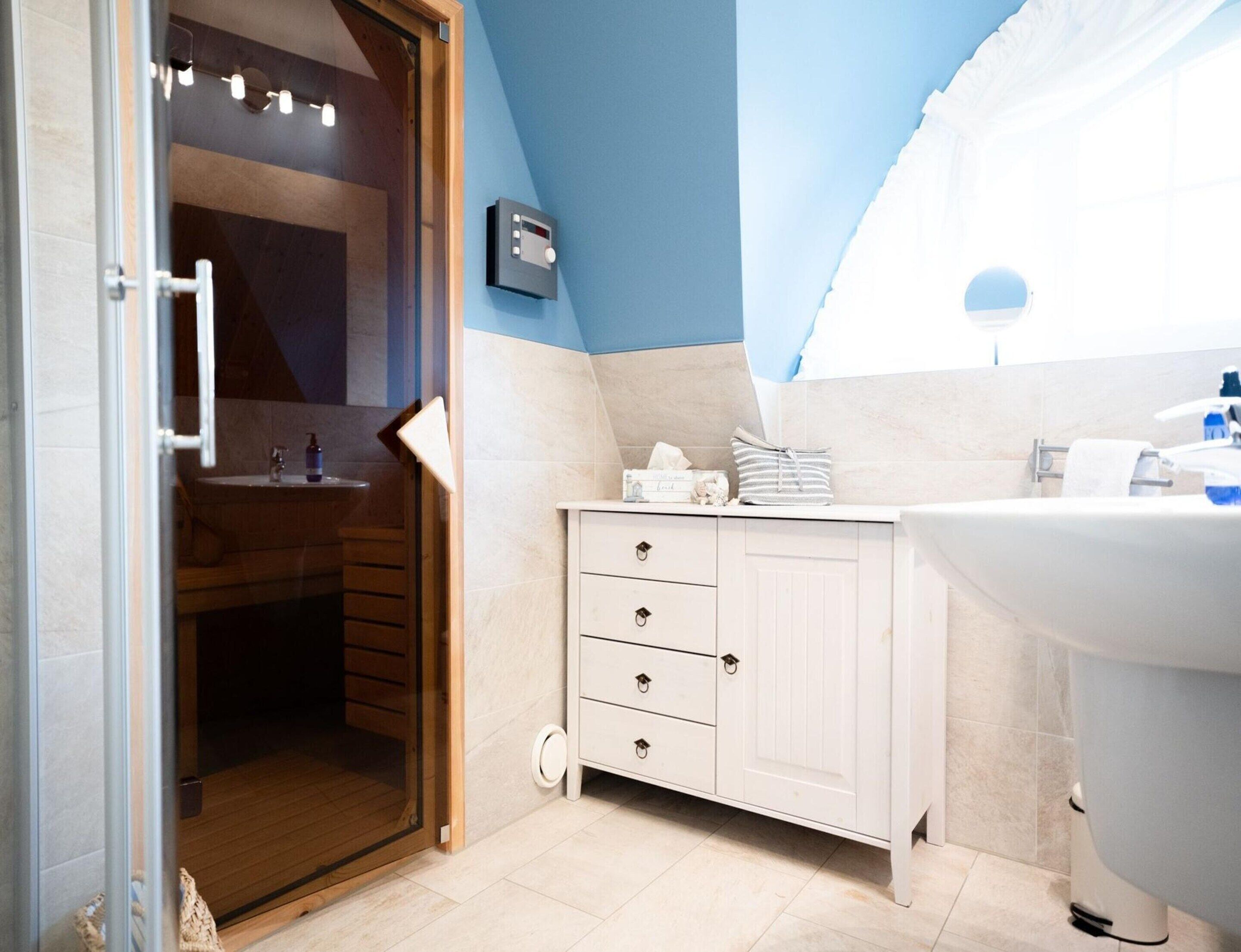 A modern bathroom with a wooden door, a white sink, and a towel rack.