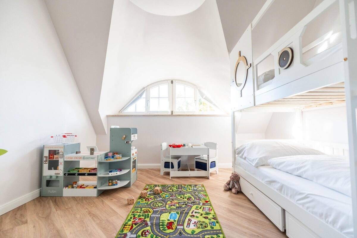 A child's playroom with a bunk bed, play kitchen, and toy storage.