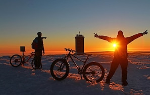 A person with arms outstretched in the snow, a bicycle, and a tower in the background. - Ferienhaus in Wernigerode mit Gemeinschaftspool (Wernigerode)