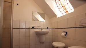Kylpyhuone, jossa on pesuallas, wc ja pieni jakkara.