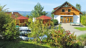 A wooden lodge with a reception area, outdoor seating, and a view of the mountains. - Chalet Near Kalkalpen National Park (Schlierbach)
