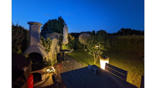 A patio with a grill, a table, and a small garden area. - Strandnaher Bungalow in Dornumersiel (Dornum)
