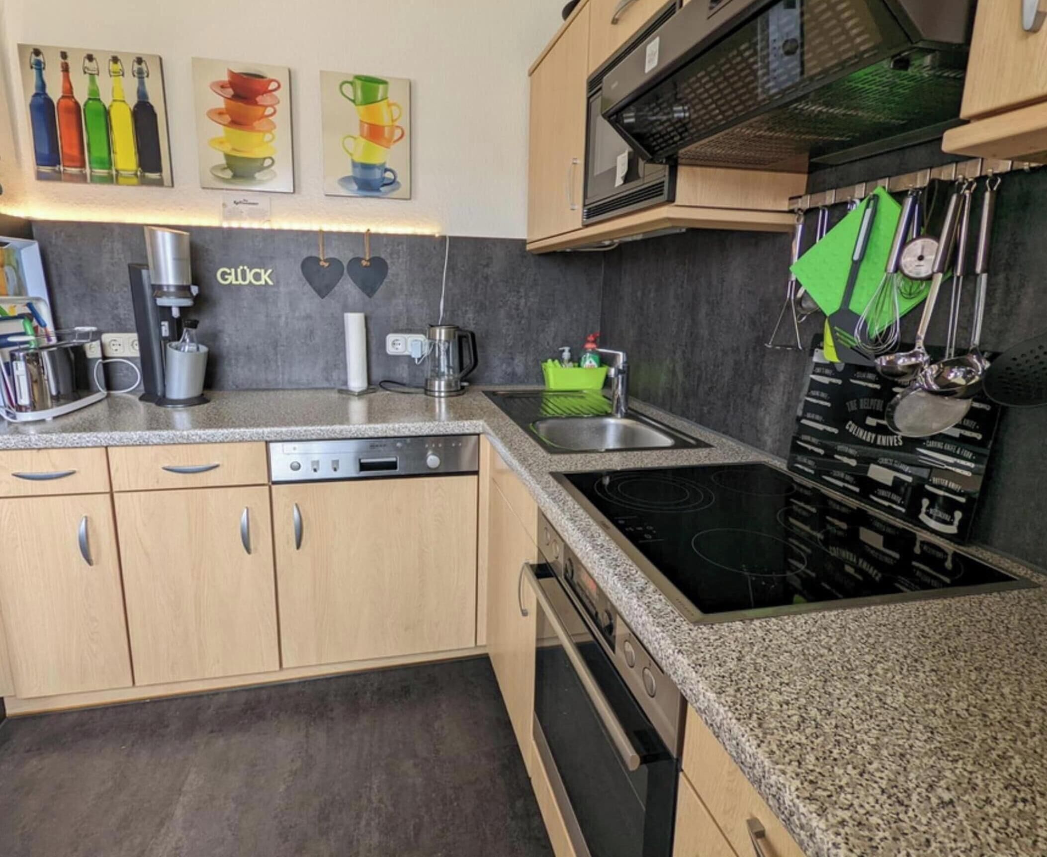 Una cocina moderna con lavavajillas, estufa y microondas. Hay decoraciones con forma de corazón en la pared y un juego de cuchillos colgados.