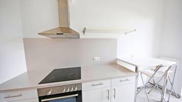 Una cuina moderna amb forn integrat, fogons i una campana extractora d'acer inoxidable.