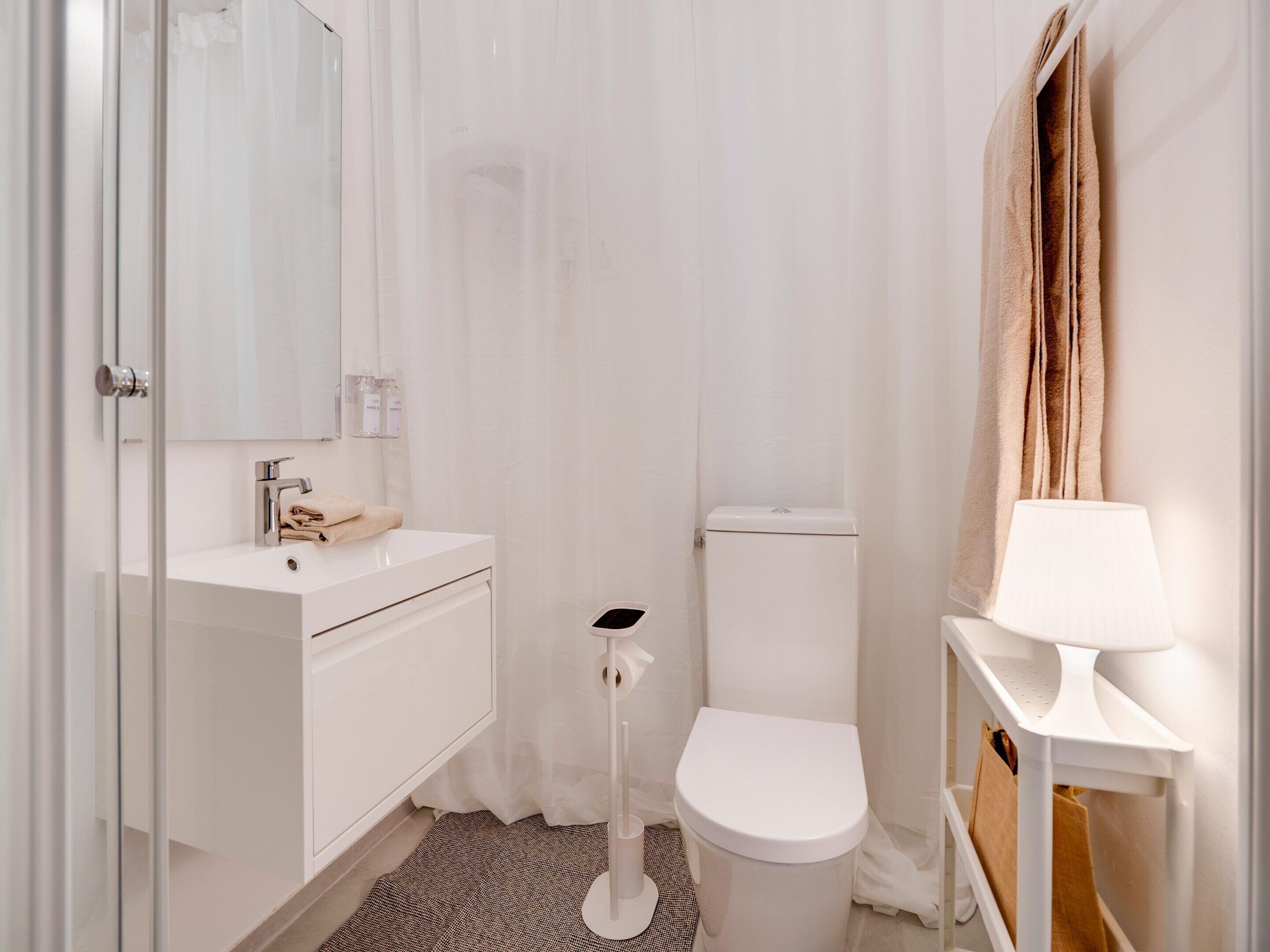 A bathroom with a white sink, toilet, and a mirror.