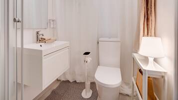 A bathroom with a white sink, toilet, and a mirror.