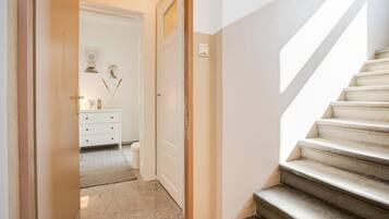 A staircase leading to a bedroom with a white door, a dresser, and a rug on the floor.