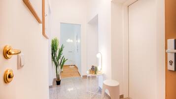 A hallway with a potted plant, a small table with a mirror, and a white door.