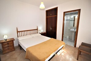 A bedroom with a bed, bedside tables, a wardrobe, a bathroom with a sink and mirror. - Apartment in Playa de Pals Near Sandy Beach (Pals)