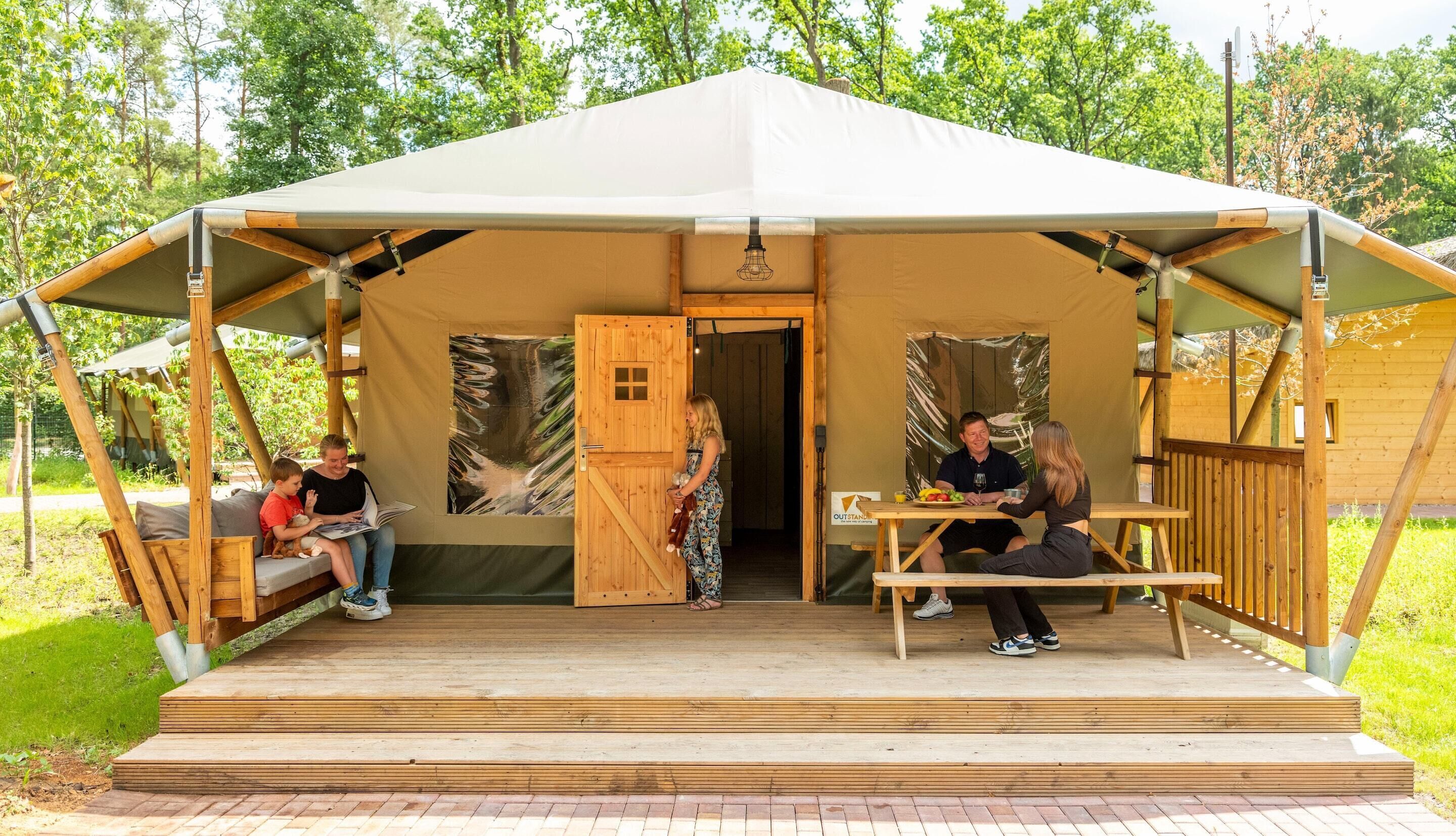 A tented structure with a wooden deck, a bench, and a table.