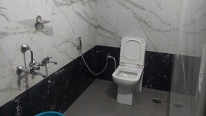 Ein Badezimmer mit Toilette, Dusche und einem blauen Eimer.
