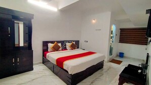 Ein Schlafzimmer mit Bett, Kleiderschrank, Nachttisch, Fenster mit Jalousien und einer Tür.