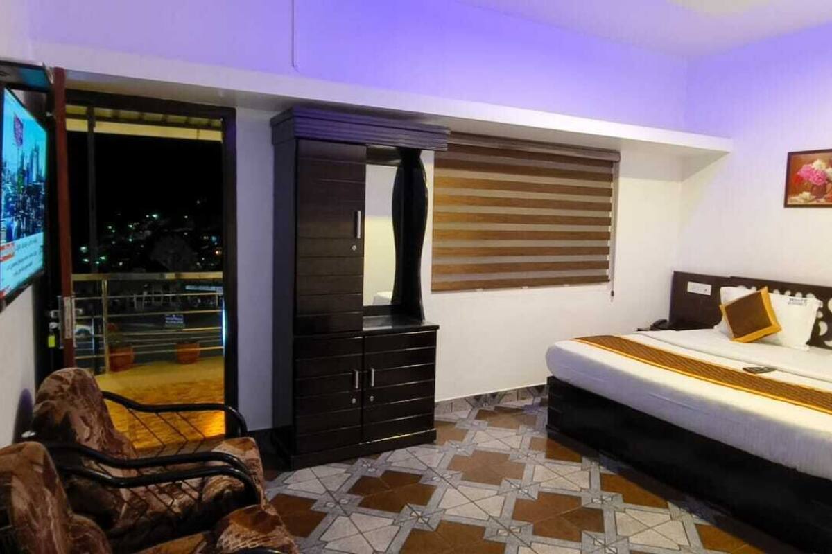 Une chambre à coucher avec un lit, une armoire, une télévision et un balcon.
