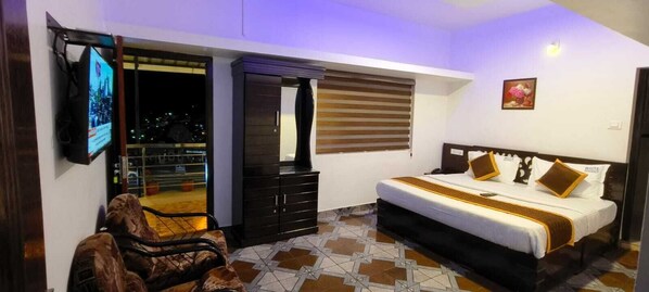 A bedroom with a bed, a wardrobe, a TV, and a balcony. - Ooty White Residency (Ooty)