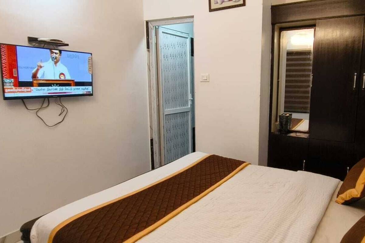 Une chambre d’hôtel avec un lit, un téléviseur fixé au mur, une armoire et une porte.
