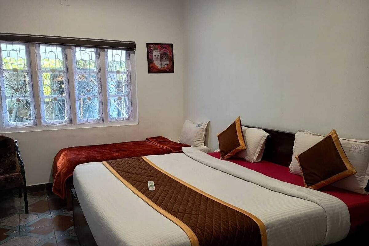 Une chambre d’hôtel avec deux lits, une fenêtre donnant sur un beau paysage et un tableau encadré au mur.