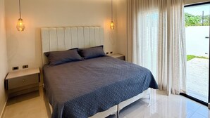 Una camera da letto moderna con un letto grande, comodini e vista sull'esterno attraverso una finestra.