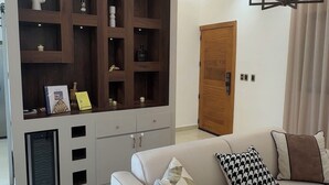 Un soggiorno moderno con un divano bianco, un mobile TV in legno e una lampada a sospensione.