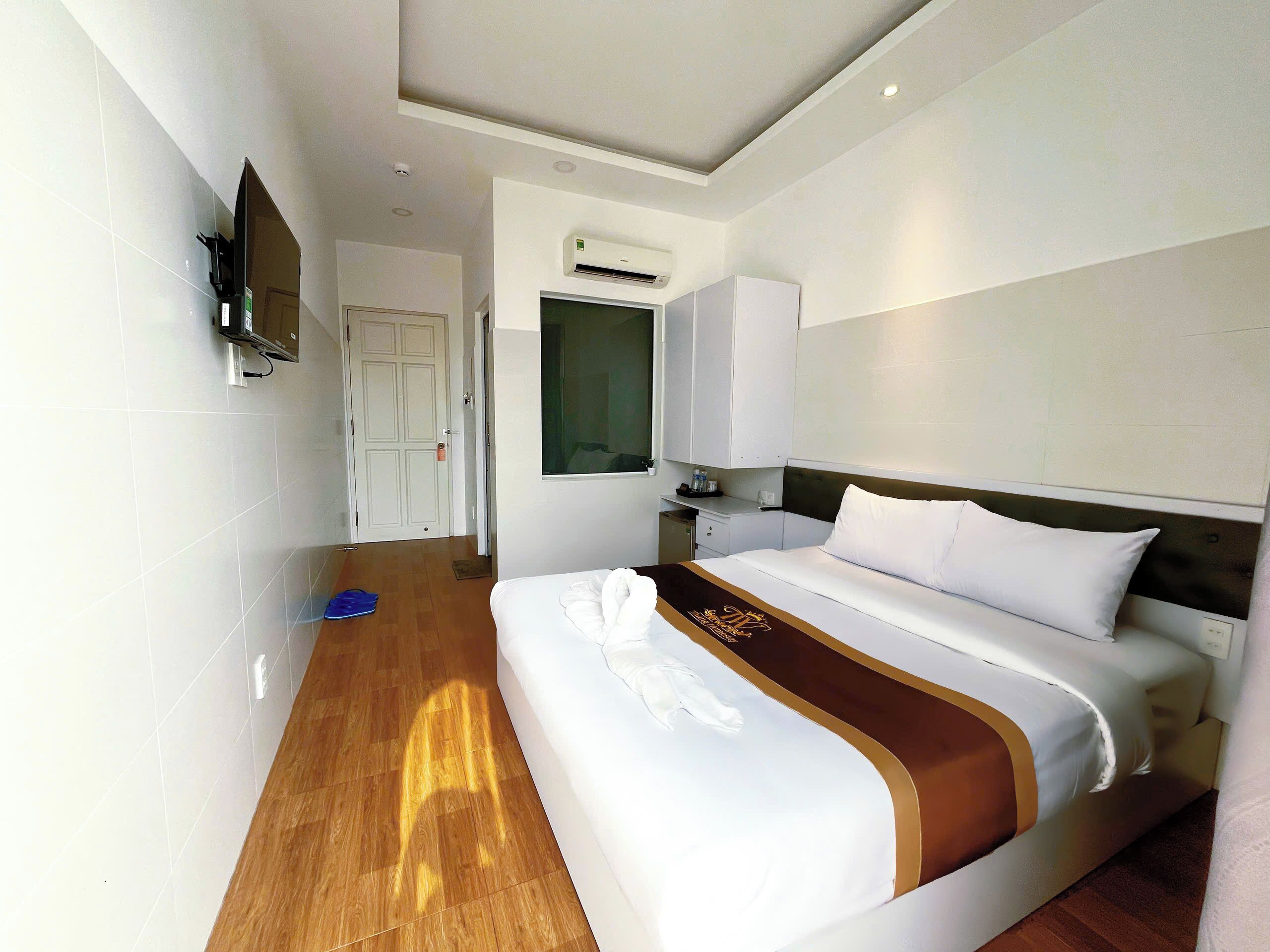Ein Hotelzimmer mit einem Bett, einem Fernseher, einer Tür und einer Klimaanlage.