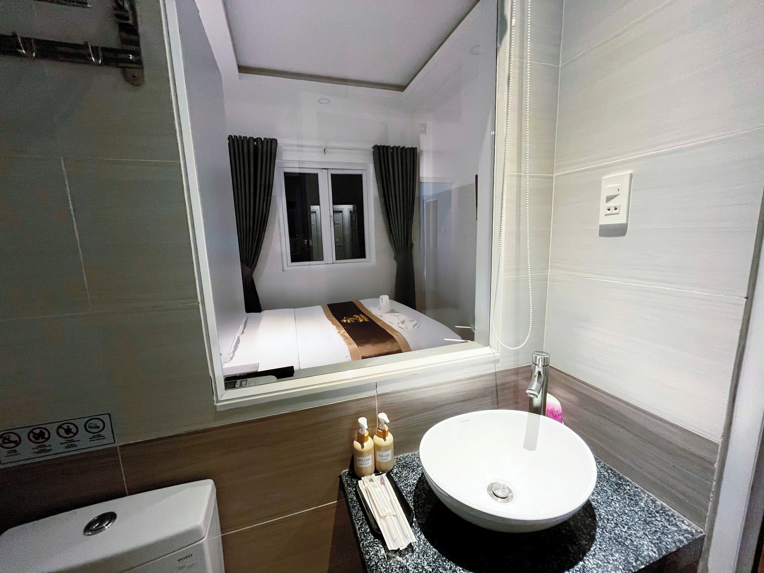 A hotel room with a bed, a bathroom with a sink, and a window with curtains.