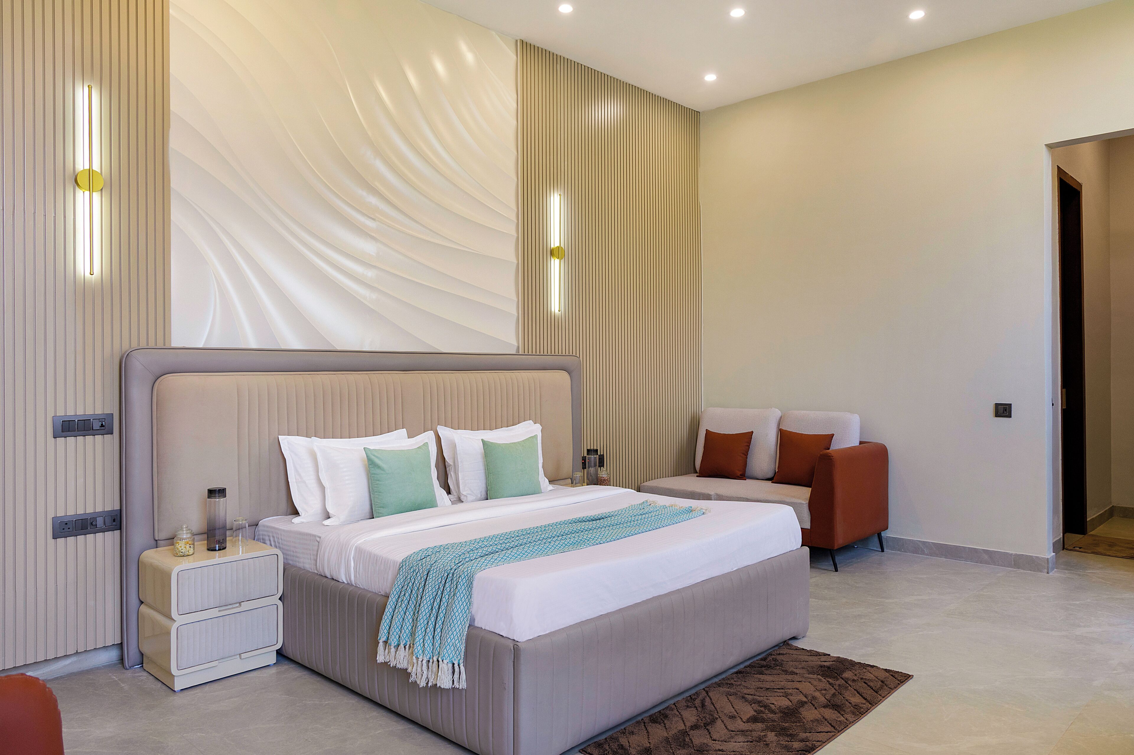 Une chambre moderne avec un grand lit, des tables de chevet, un coin salon et une porte.