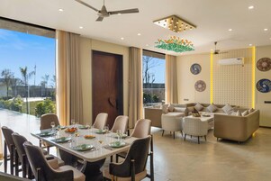 Un comedor moderno con una mesa preparada para seis personas, un conjunto de sofás y un ventilador de techo.
