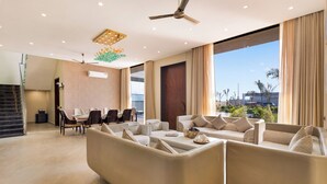 Una sala de estar moderna con un conjunto de sofás, comedor y un ventanal con vistas.