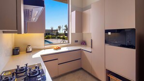 Cocina moderna con ventana, electrodomésticos integrados y vista a palmeras.